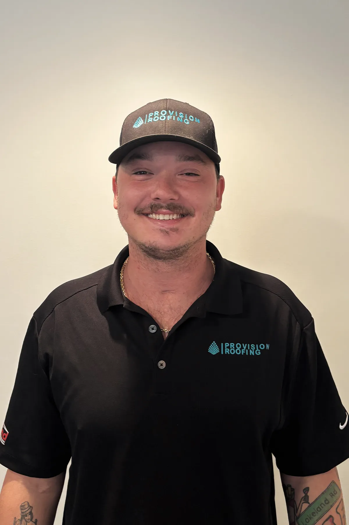 Man wearing a black Provision Roofing cap and polo shirt, smiling against a plain background.